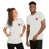 A woman and a man smiling, wearing matching light gray t-shirts with a small red design.
